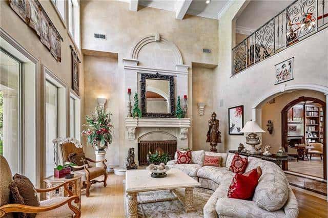 The living room has a soaring beamed ceiling and a fireplace topped with a large ornate mirror.
