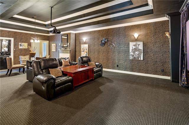 The large media room features a step ceiling and black recliners flanking the polished wooden table.