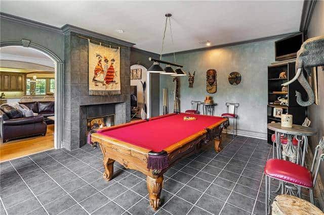 The game room offers multiple seating and a billiard table under the black dome pendants.