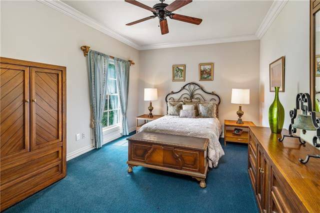 This bedroom has blue carpet flooring and a white framed window dressed in lovely curtains.