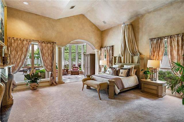 The spacious primary bedroom has a high vaulted ceiling and a sitting area defined by interior columns.