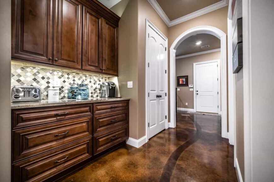 Coffee bar with wooden cabinets and a granite counter topped with stainless steel appliances and translucent blue jars.