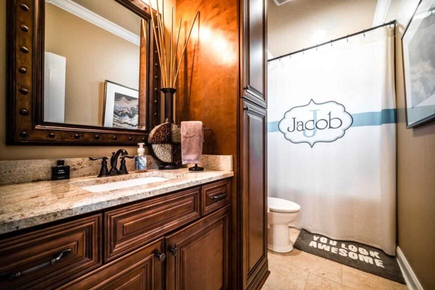 The bathroom has a sink vanity, a toilet, and a shower and tub combo enclosed in a white curtain.