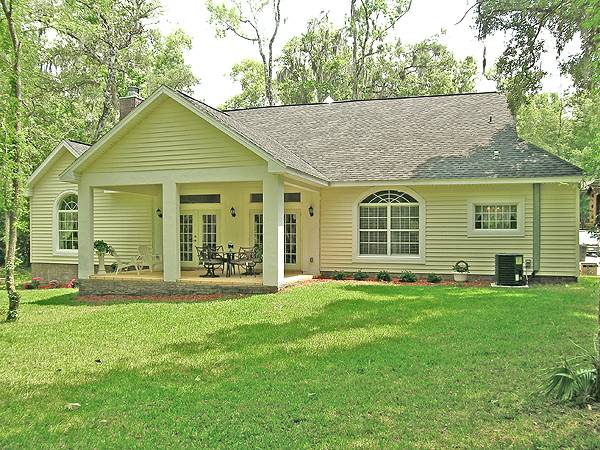 Home's rear view showing the yellow exterior siding and a covered porch supported by large columns.