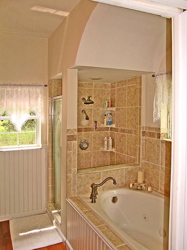 The primary bath is equipped with a deep soaking tub and a walk-in shower complemented with a small white rug.