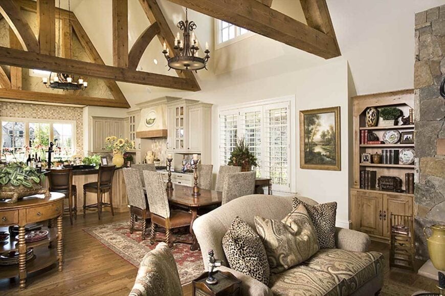 This open layout view shows the living room, dining area, and kitchen under the vaulted ceiling with exposed beams.