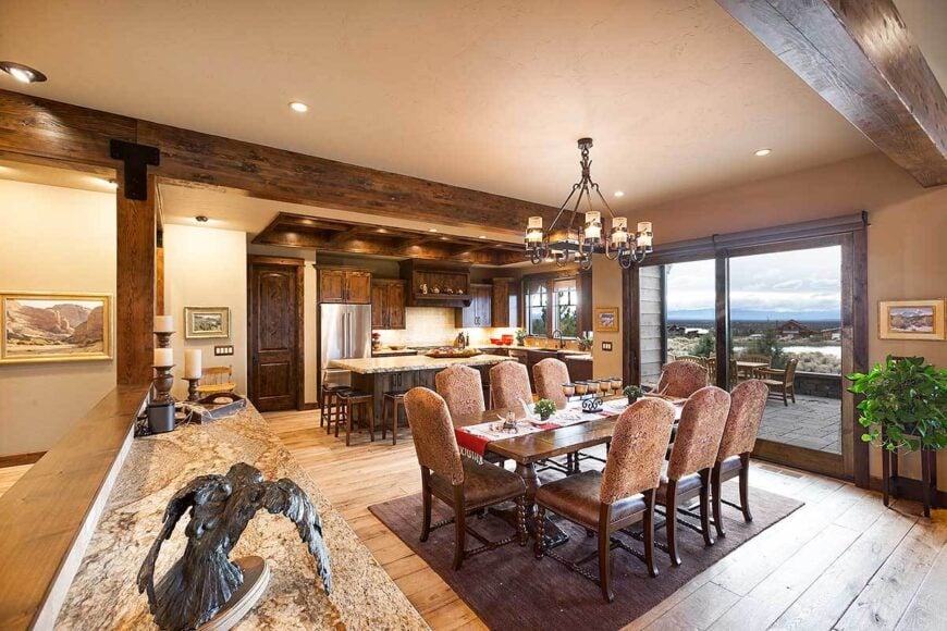 The dining room offers brown leather seats and a rectangular dining table under the ornate chandelier.