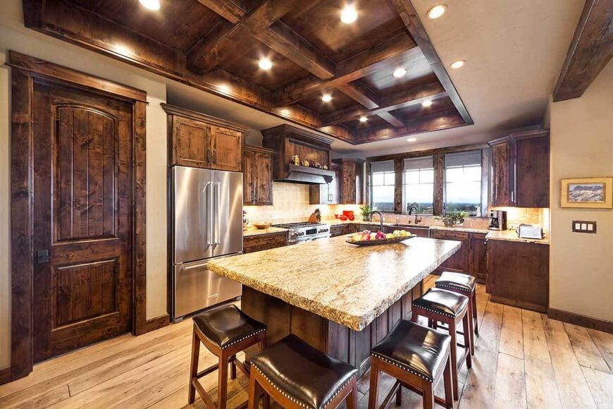 The kitchen is flooded with natural and ambient lights coming from the glazed windows and recessed lights fitted on the coffered ceiling.