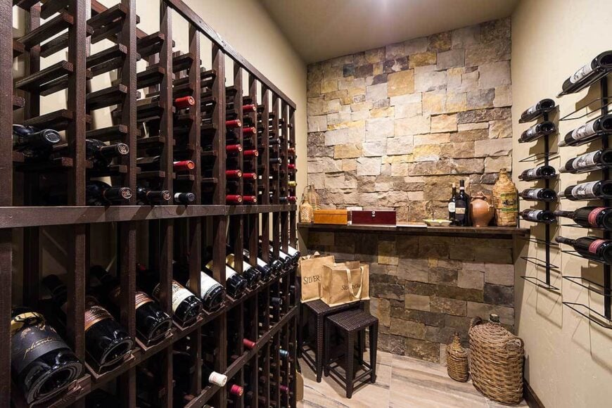 Wine cellar with column shelving, wall-mounted racks, and a floating shelf fixed against the brick accent wall.