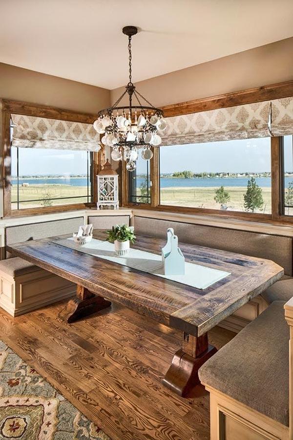 A breakfast nook offering a built-in seat and a rustic dining table under the wrought iron chandelier.