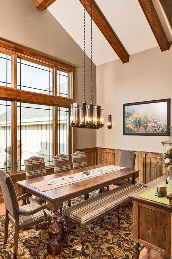The dining room has a glass chandelier and a rectangular dining table surrounded by checkered chairs and a matching bench.