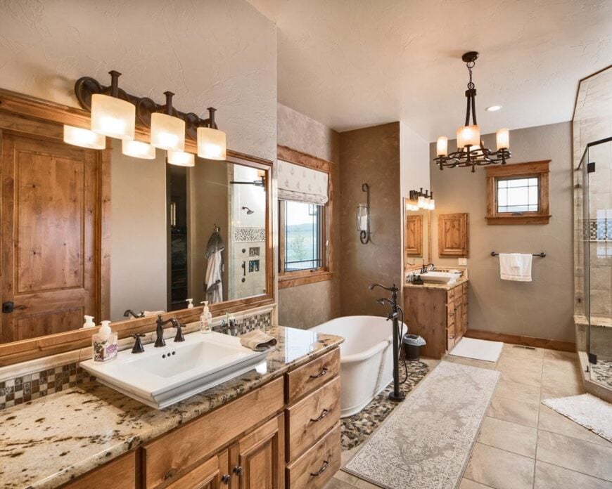 Vessel sink vanities flank the freestanding tub that's paired with wrought iron fixtures.