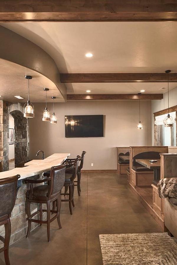 Recreation room with multiple sitting areas and a curved wet bar illuminated with glass pendants.
