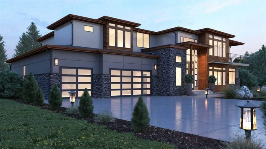 The angled front view shows the captivating stone accents, beautiful wood trims, a 4-car garage, and a warm entry guarded by large potted plants.