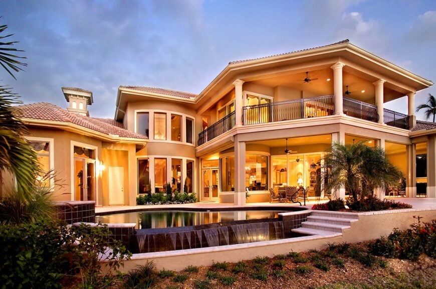 Rear exterior view showing the lavish pool, covered lanai, and upper balcony enclosed in wrought iron railings.