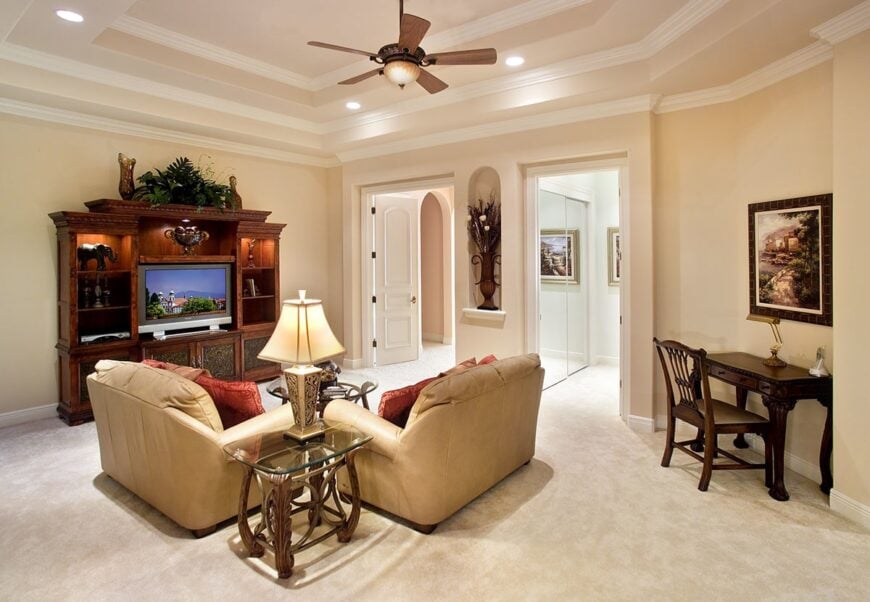Loft family room with beige leather sofas, a TV, and a desk situated on the corner.