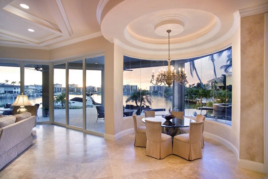 The breakfast nook features a round dining set and a candle chandelier hanging from the round drop ceiling.