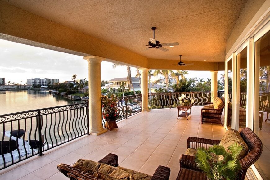 Upper balcony with impressive views of the magnificent lake. It is filled with wicker seats, a wooden table, and wrought iron ceiling fans.