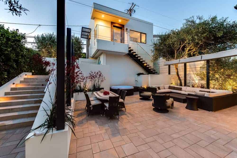 This is the charming backyard patio with terracotta flooring bricks to complement the black outdoor furniture of the dining and sitting area.