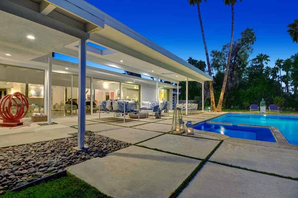 This is the view of the covered patio beside the poolside area. This showcases the beautiful concrete slab walkways that transition to pebbled grounds and the grass lawn.