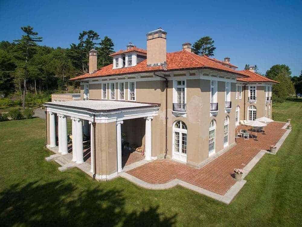 This aerial view of the side of the house shows the lovely patio fitted with an outdoor dining area on the terracotta brick flooring edged with concrete before it reaches the grass lawn.