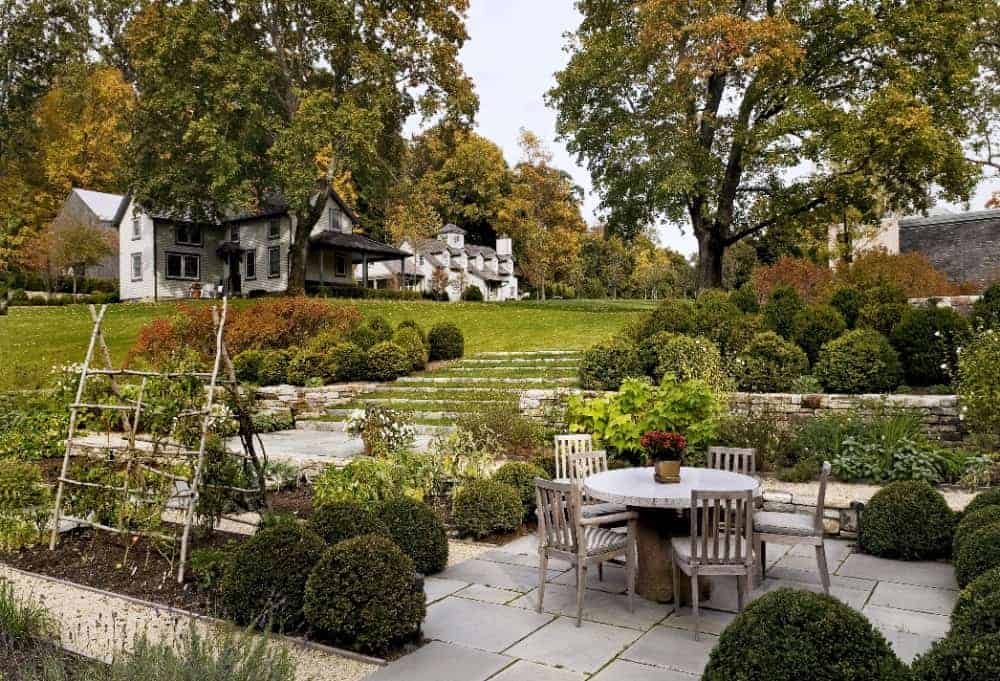 This is the gorgeous patio that has a concrete slab flooring surrounded by landscaping filled with shrubs and grass to complement the outdoor dining set.