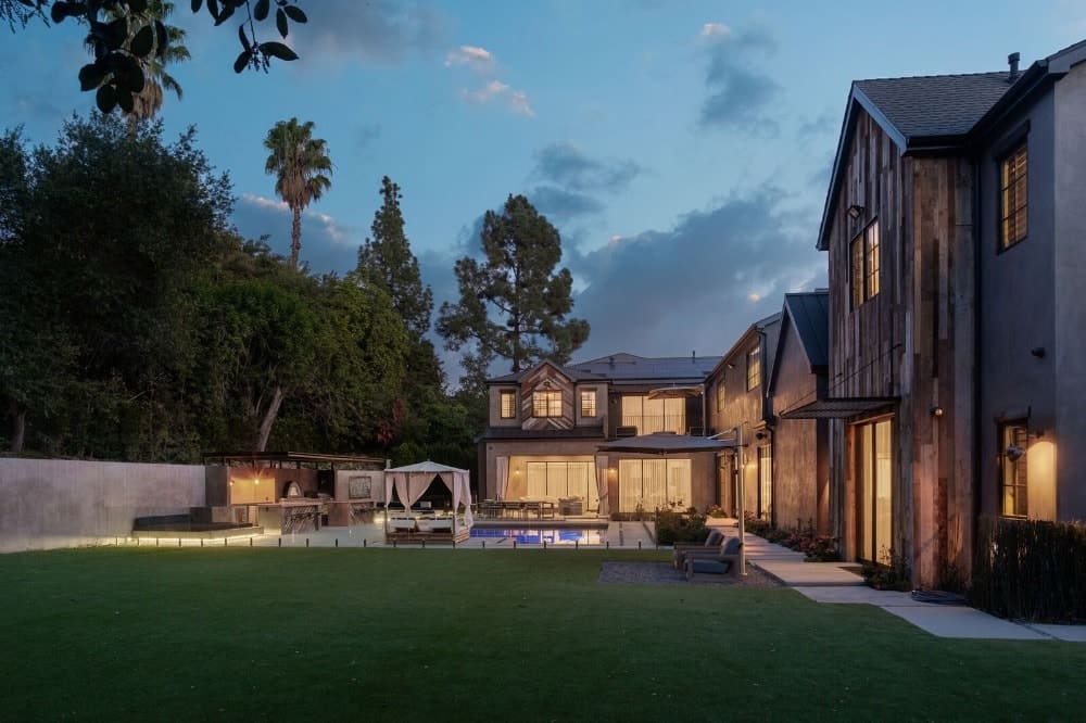 Here you can see the edge of the large patio with a concrete floor transitioning to concrete slab walkways leading to the lush green well-maintained grass lawn.