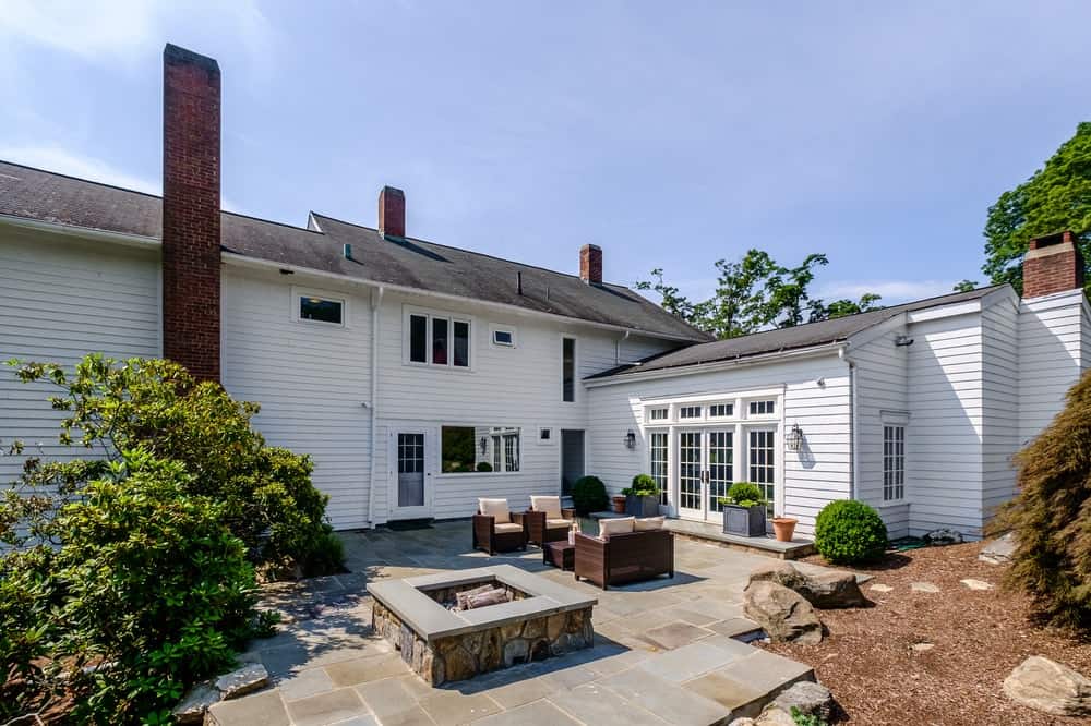 This is the back of the house fitted with an outdoor sitting area and a charming stone firepit to bring warmth to the place. It has a stone tile floor adorned with decorative rocks at the edges.
