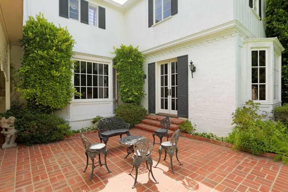 An open-air porch with tasteful seats and an inside table set in the center. The ground surface of this outside zone looks totally flawless.