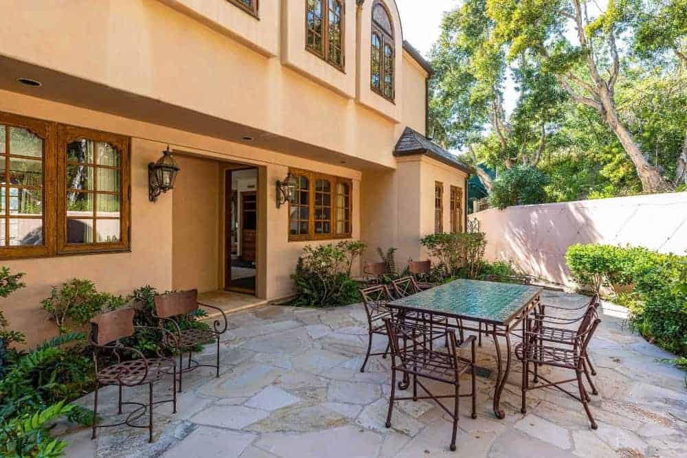 This patio area features a metal dining table paired with metal chairs and a doorway that leads inside the house.