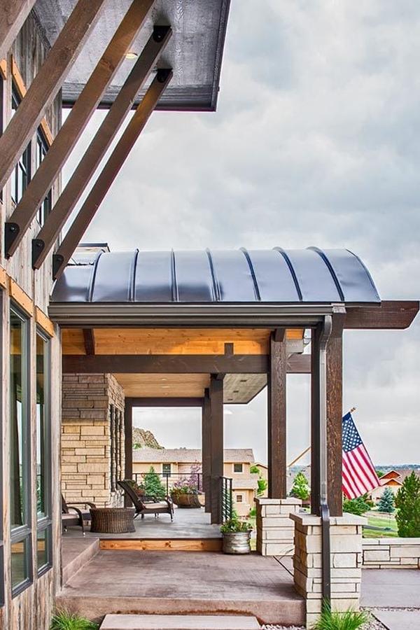 The front porch framed with decorative columns is filled with cushioned seats and a wicker coffee table.