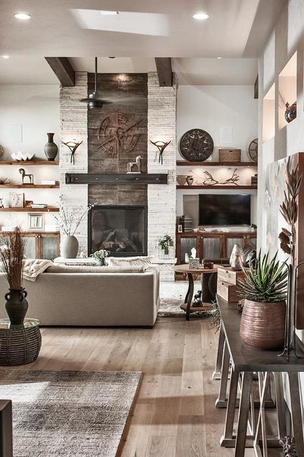 The living room offers a gray sofa, wooden tables, and a glass-enclosed fireplace flanked with floating shelves.