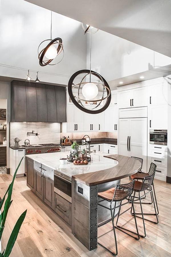 Large spherical pendants illuminate the kitchen with white cabinetry and a center island fitted with a curved eating counter.