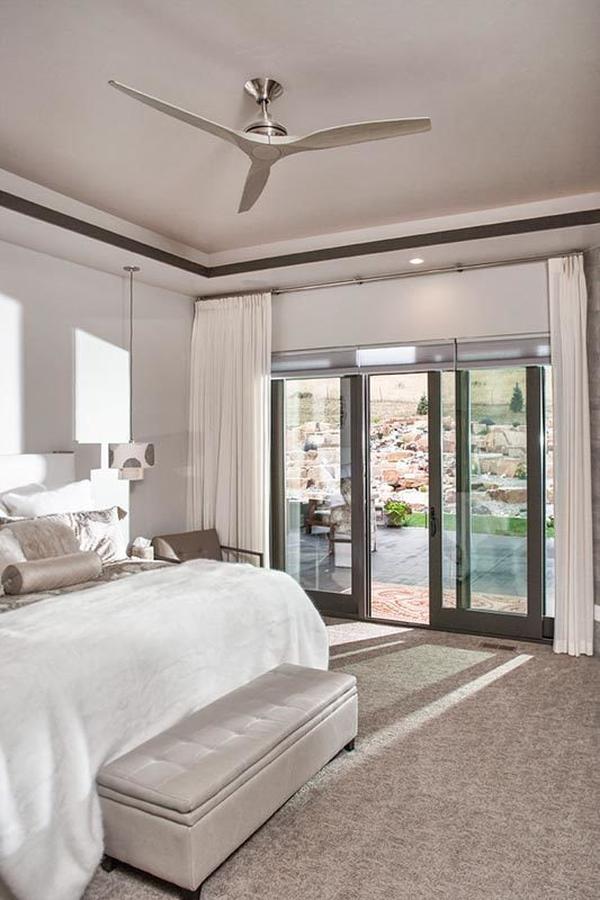 The primary bedroom showcases gray carpet flooring and glass sliders that lead out to the rear covered patio.