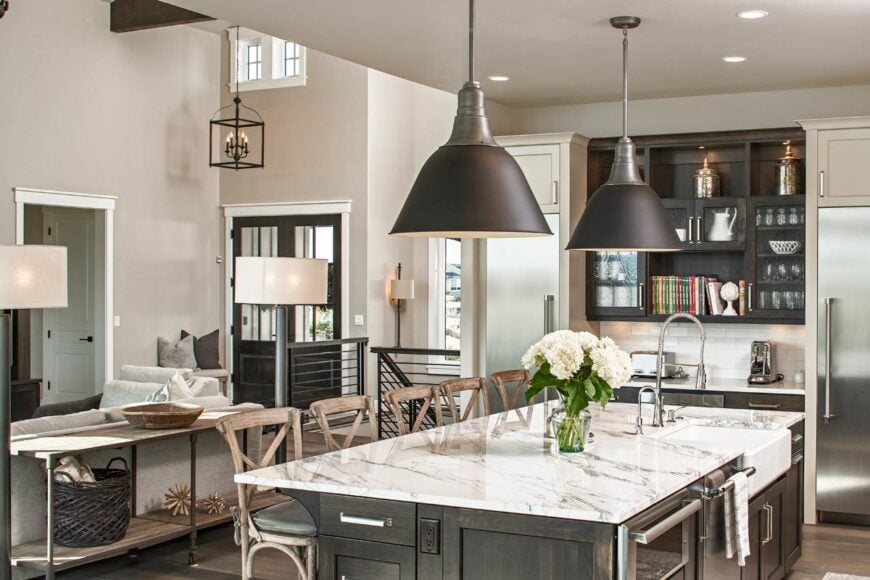 There are dark wood cabinets adjacent to the large island flanked with stainless steel appliances.