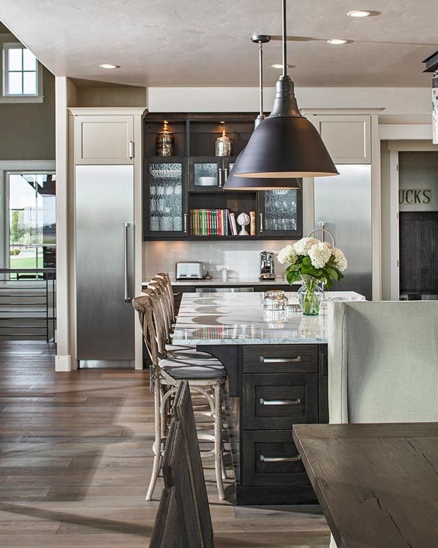 A closer look at the kitchen island with dark wood pull-outs and white marble countertop lit by oversized dome pendants.
