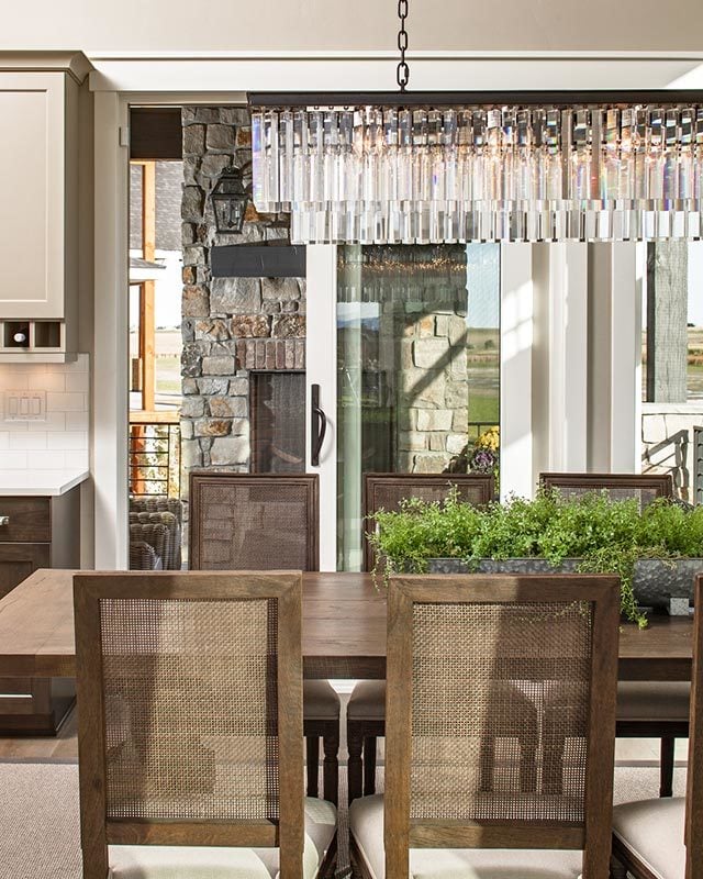 The glass cascading chandelier is suspended above a rectangular dining table surrounded by wooden cushioned chairs.