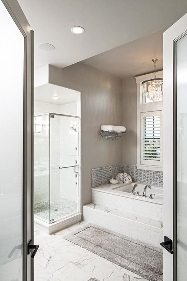 View of the primary bath from the water closet showcasing gray walls and a marble-tiled flooring topped with a rectangular rug.