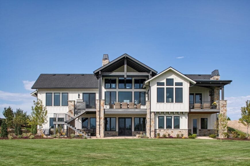 Daylight view of the rear exterior showcasing the covered decks and balconies framed with wrought iron railings and stone columns.