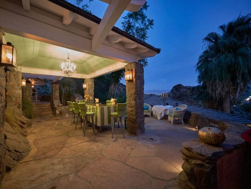 This is a look at the beautiful covered patio fitted with an outdoor dining set standing on a mosaic stone flooring bordered with decorative rocks and stone walkways.