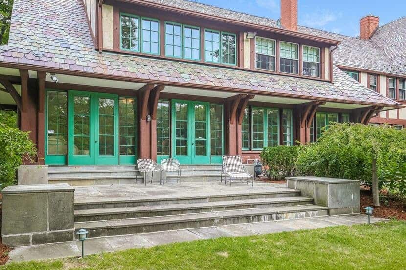 This is the view of the back of the house from the grass lawn of the backyard. You can see here that the patio has a concrete floor with steps and planters on the side before it transitions to the grass lawn.