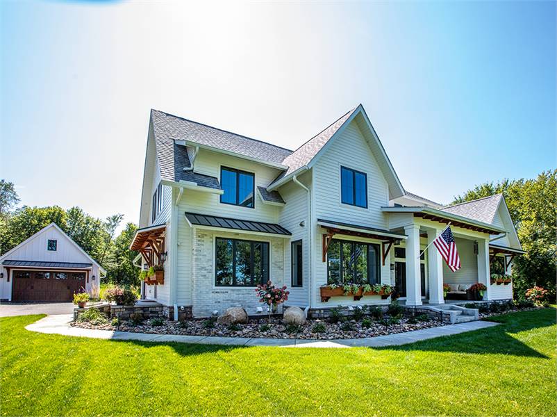 An angled front view showing the white exterior siding and a covered front porch lined with large columns.