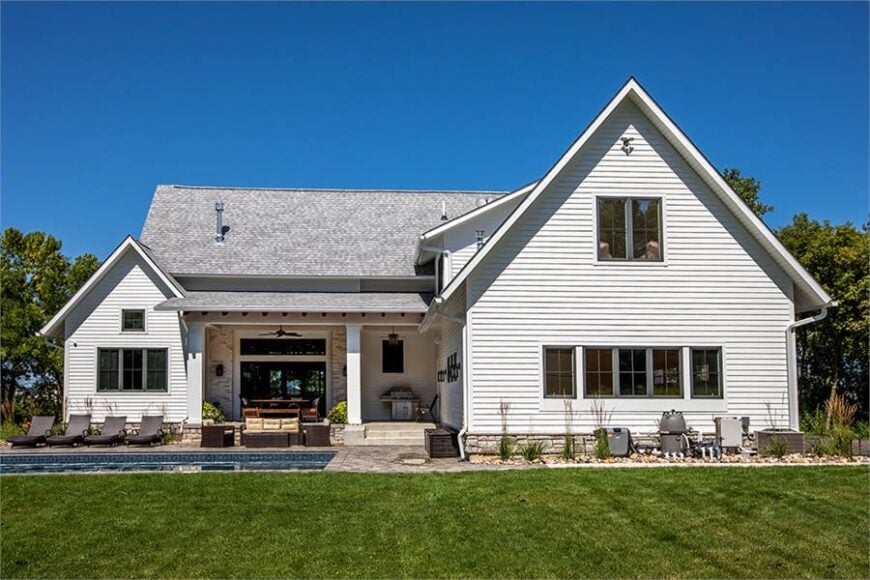 Home's rear view with a covered lanai that's filled with outdoor living and a summer kitchen.