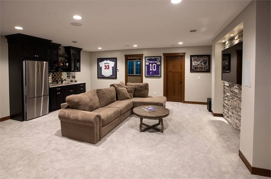 Family room with an L-shaped sectional and a round coffee table facing the TV that's fixed against the brick accent wall.