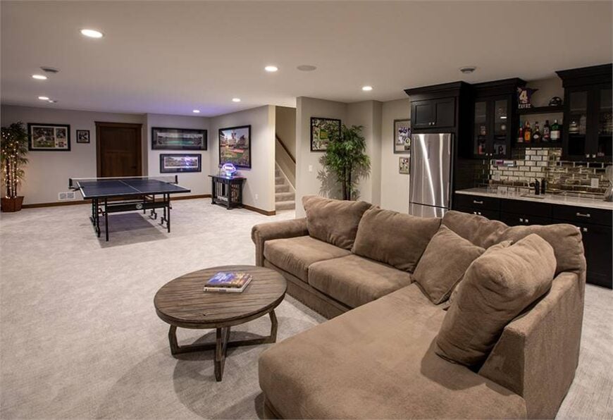 There's a bar behind the sofa and a pingpong table on the side. It is complemented by a dark wood console table.