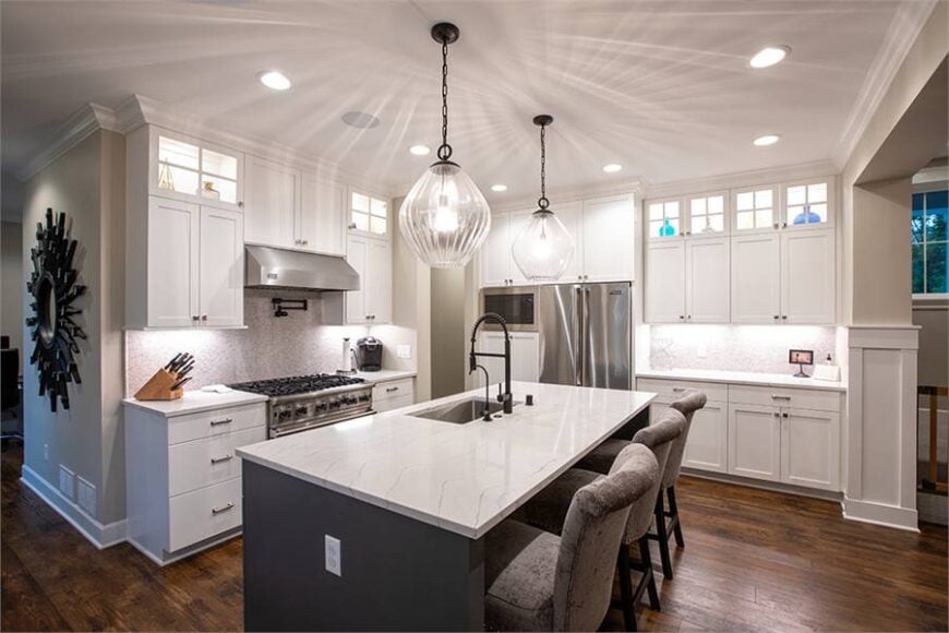 The kitchen is equipped with stainless steel appliances, white cabinets, and an undermount sink fitted on the marble top island.
