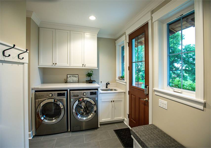 The laundry room is equipped with front-load appliances, white cabinets, and an undermount sink.