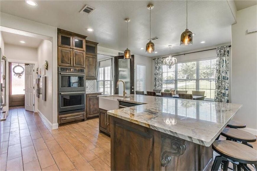 Kitchen with black appliances and an L-shaped island fitted with a farmhouse sink.