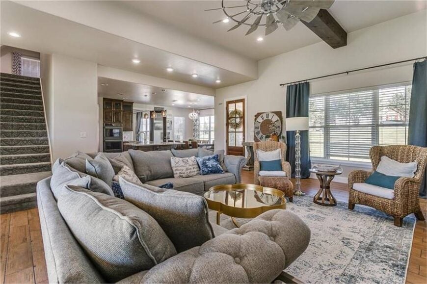 An ample amount of natural light streams in through the white framed window covered in roller blinds and blue draperies.