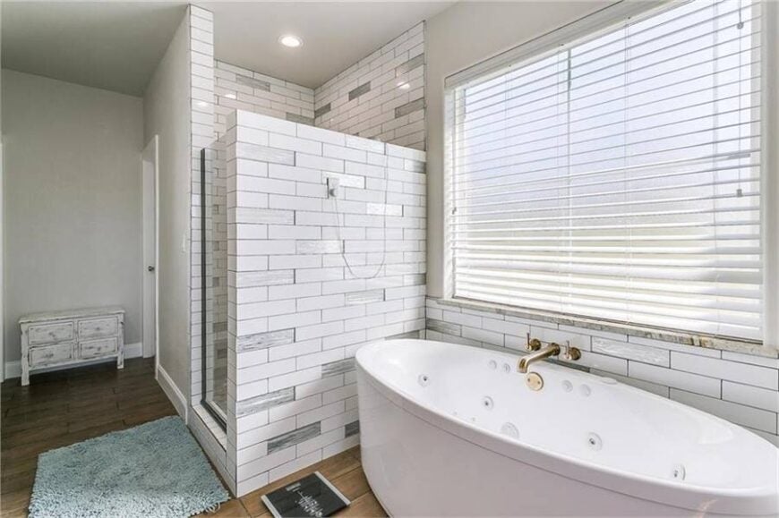 A gray shaggy rug over the hardwood flooring complements the shower area that's placed next to the whirlpool tub.